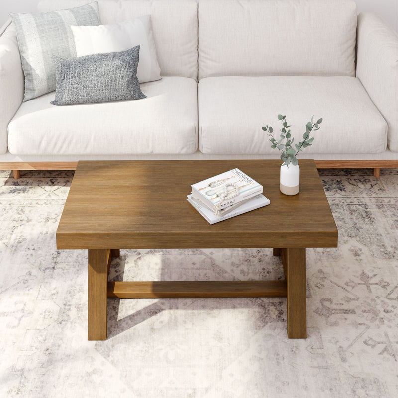 White couch with wooden coffee table, decorative books, and vase, in a modern living room setting.