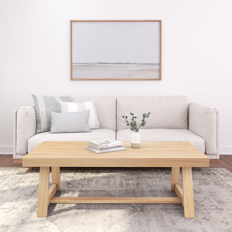 Modern minimalist living room with a beige sofa, wooden coffee table, decorative pillows, and a simple art piece, perfect for contemporary home decor inspiration.