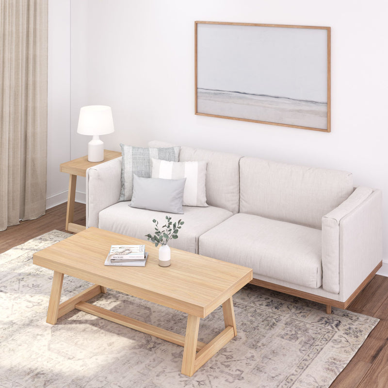 Cozy modern living room with beige sofa, wooden coffee table, white lamp, and minimalist decor.