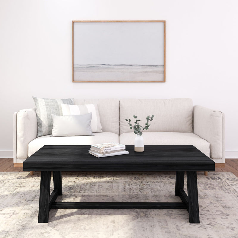 Modern minimalist living room with beige sofa, black coffee table, and abstract wall art.