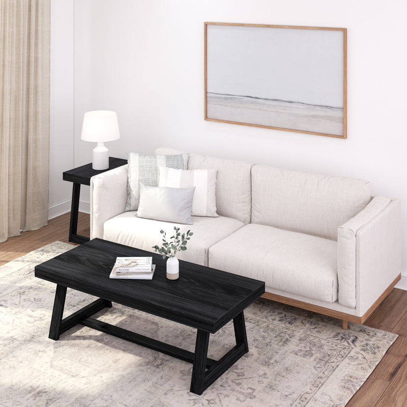 Modern living room with cream sofa, black coffee table, decorative pillows, and minimalist artwork on the wall.