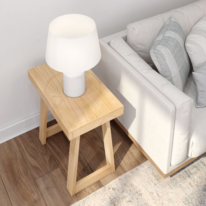 Minimalist living room with wooden side table, modern white lamp, and cozy gray sofa.