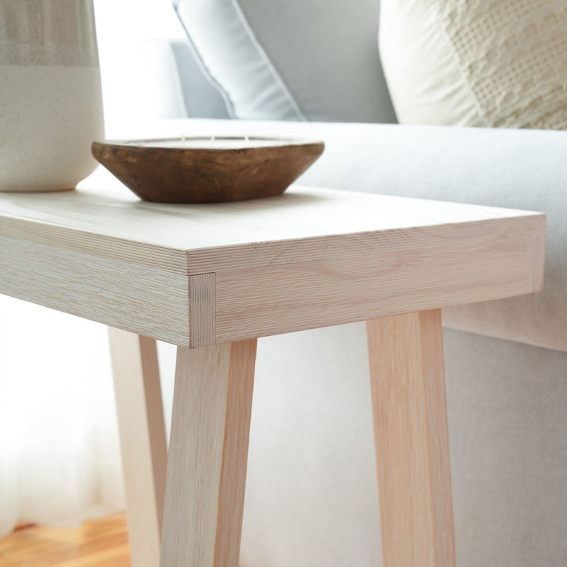 Minimalist wooden side table with a rustic decorative bowl in a modern living room setting.