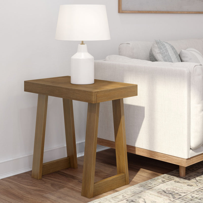 Wooden side table with a white lamp next to a beige sofa in a modern living room setting.