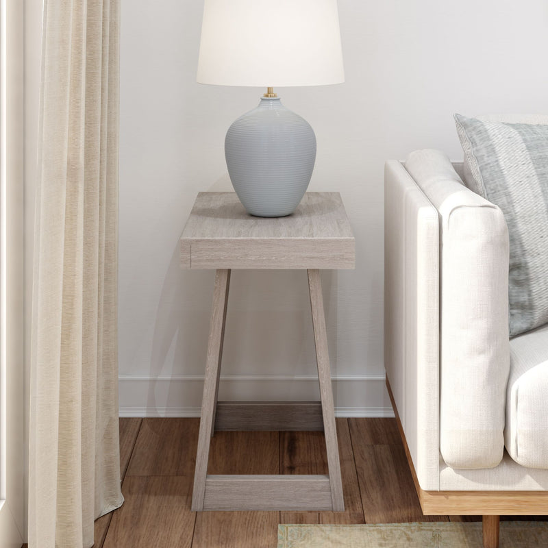 Minimalist living room with a light wood end table, modern ceramic lamp, and beige sofa.