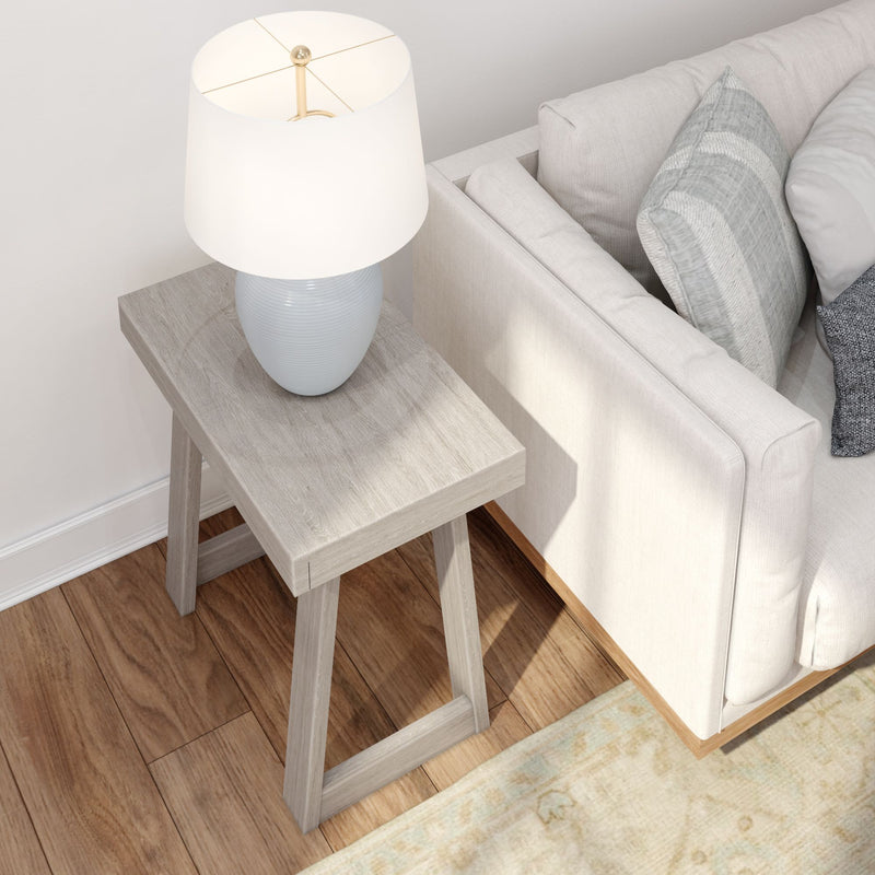 Modern wooden side table with decorative lamp beside beige couch in cozy living room.
