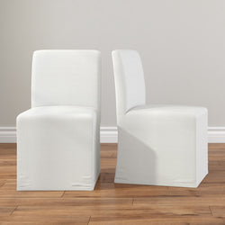 Pair of white slipcovered armless parson dining chairs on hardwood floor, modern minimalist upholstered dining room seating