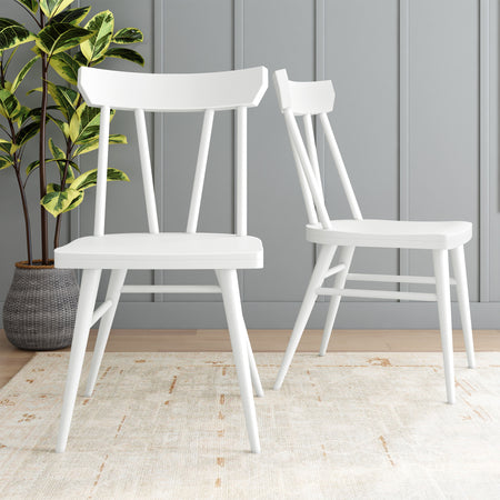 White modern dining chairs in a stylish interior with gray panel wall and potted plant.