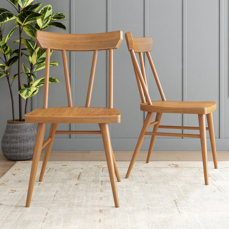 Two modern wooden chairs in a stylish room with gray paneling and a green potted plant.