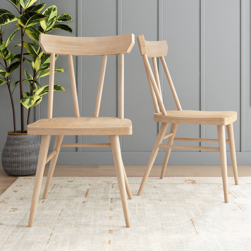 Two modern wooden dining chairs on a light area rug in a stylish, contemporary room setting.