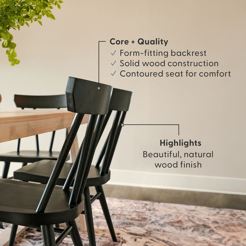 Black wooden spindle-back dining chairs with contoured seats and solid wood construction beside a light wood farmhouse table and hanging plant