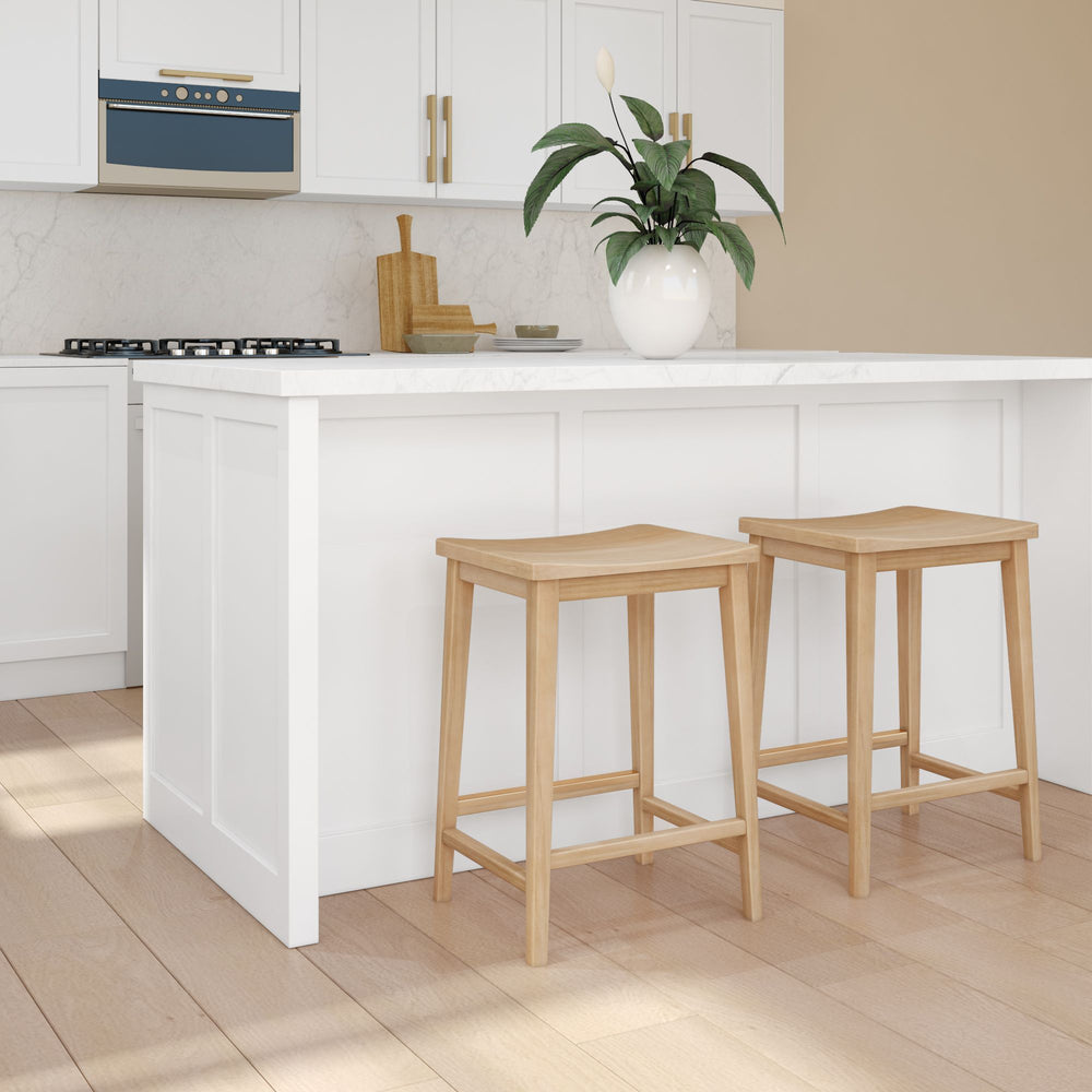 Modern kitchen interior with wooden stools and white island countertop.