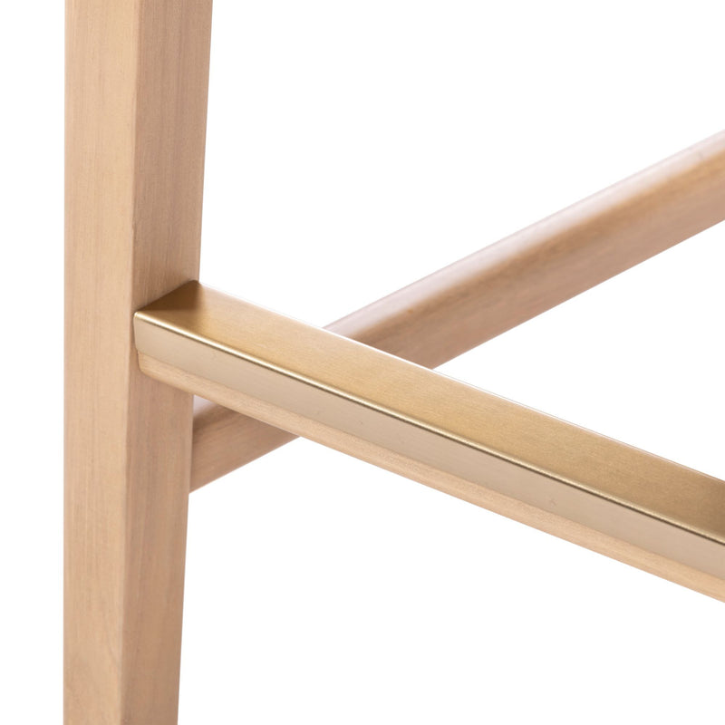 Close-up of a beige wooden chair leg with a brass crossbar, showcasing modern minimalist furniture design.