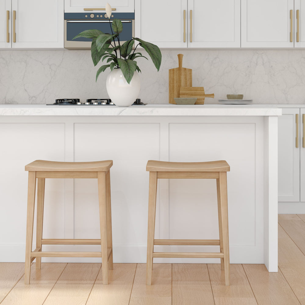 Modern white kitchen with wooden bar stools and a potted plant on a marble countertop.