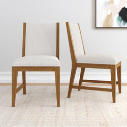 Modern wooden dining chairs with white cushions on a textured rug.