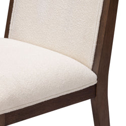 Close-up of a modern dining chair with cream fabric upholstery and wooden frame.