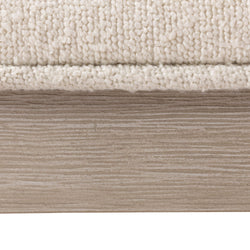 Close-up of cream loop-pile area rug edge on light oak wood plank floor — neutral beige rug texture for living room decor