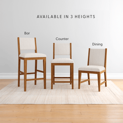 Wooden dining, counter, and bar height chairs with white cushions displayed on a rug.