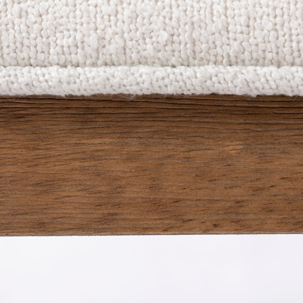 Close-up of textured white fabric upholstery on a rustic wooden frame.