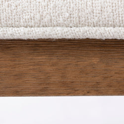 Close-up of textured white fabric upholstery on a rustic wooden frame.