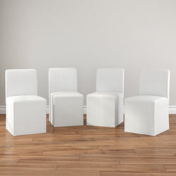 Set of 4 white slipcovered armless dining chairs on hardwood floor in neutral modern farmhouse dining room