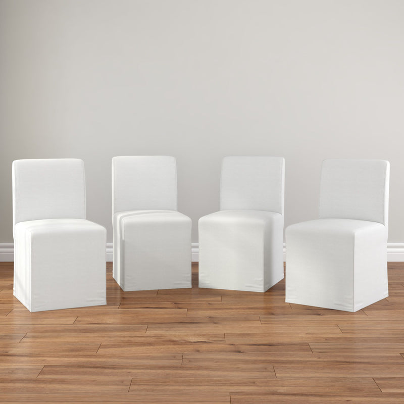 Set of 4 white slipcovered armless dining chairs on hardwood floor in neutral modern farmhouse dining room