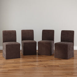 Set of 4 brown upholstered armless dining chairs on hardwood floor against neutral wall, plush microfiber slipcover, minimalist dining room seating