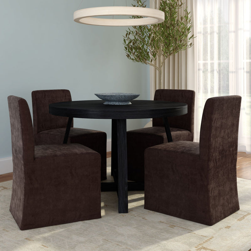 Modern dining room with round black wood table, four dark brown upholstered slipcovered chairs, circular pendant light, potted olive tree, light blue walls and large window