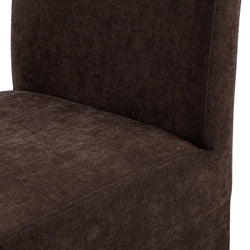 Close-up of chocolate brown upholstered dining chair seat and back showing soft textured fabric and visible seam stitching, modern armless design