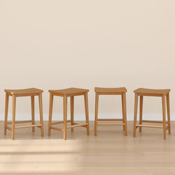 Four wooden stools arranged in a row on a light wood floor with a neutral beige background.