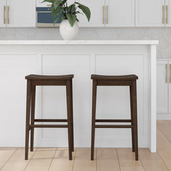 Dark wooden bar stools in a modern white kitchen with a large potted plant.