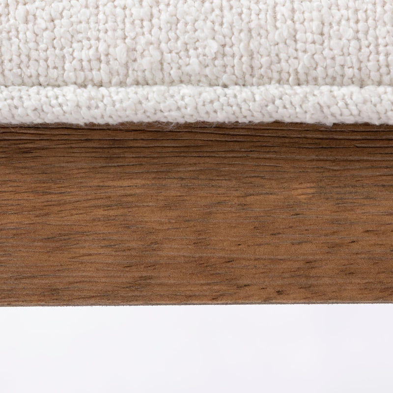Close-up of a wooden table edge next to a textured white fabric upholstery, highlighting modern interior design materials.