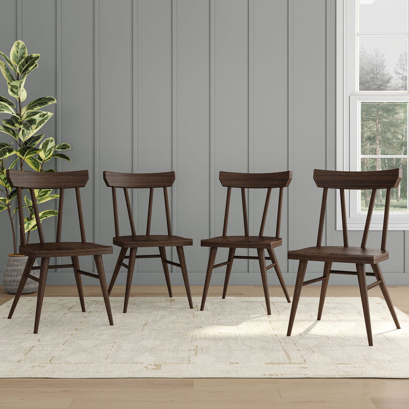Four modern wooden dining chairs on a light carpet in a stylish room with paneled walls and a potted plant.