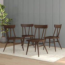 Set of four mid-century modern wooden dining chairs on a rug in a stylish living room.