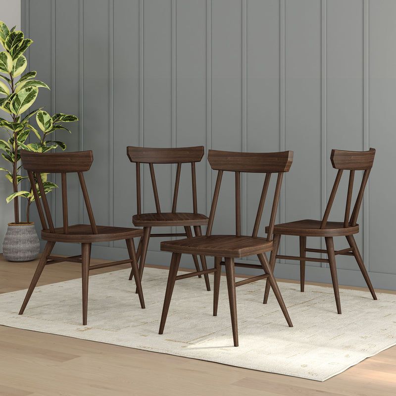 Set of four mid-century modern wooden dining chairs on a rug in a stylish living room.