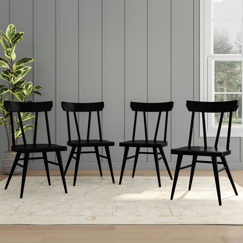 Set of four modern black dining chairs in a stylish room with light gray paneled walls and natural light from a window.