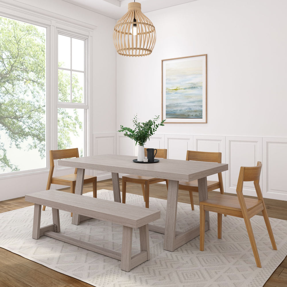 Modern dining room with wooden table, chairs, and bench, white walls, large window, stylish light fixture, and nature artwork.