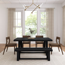 Modern farmhouse dining room with black wood dining table and bench, wooden chairs, beige curtains, large windows, eucalyptus centerpiece and abundant natural light.