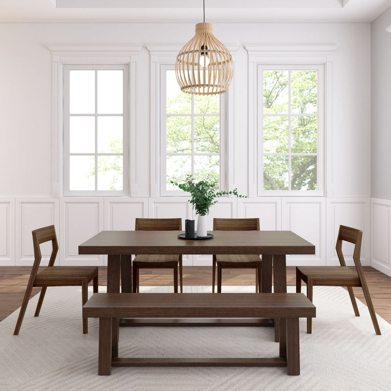 Minimalist modern dining room with dark wood dining table and bench, four wooden chairs, rattan pendant light, vase of greenery, large bright windows and white paneled walls