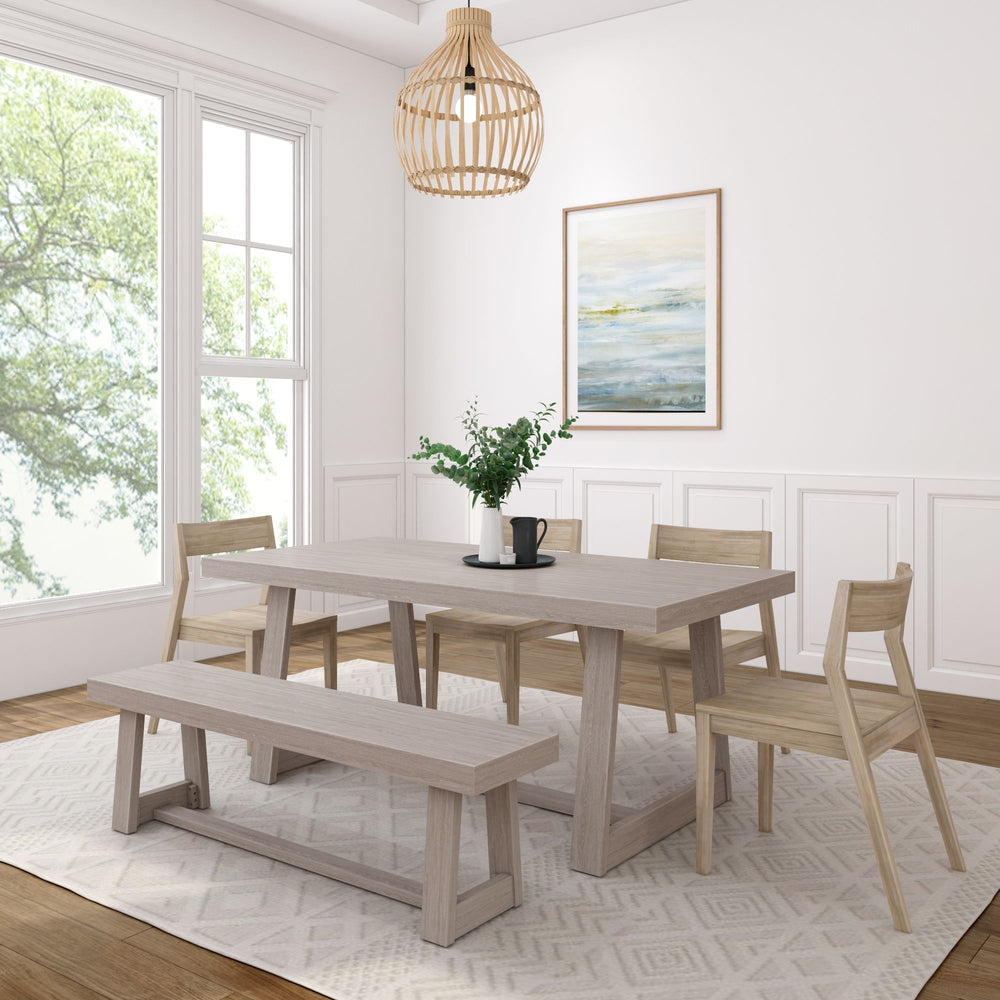 Modern dining room with light wooden table, bench, and chairs, featuring a decorative plant centerpiece, large window view, and wall art.