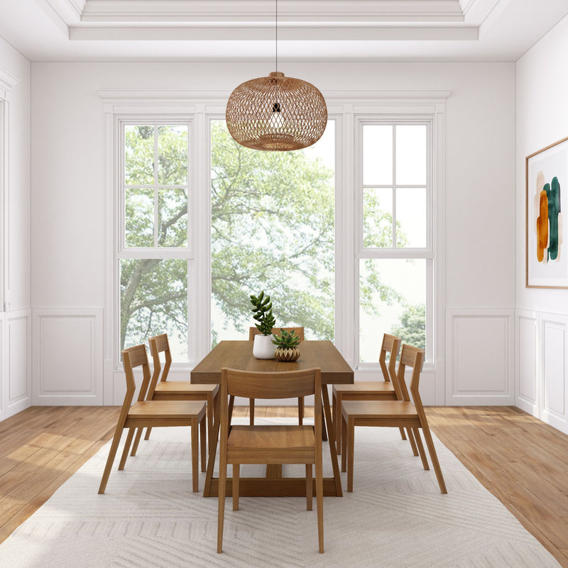 Modern dining room interior with wooden table, chairs, and hanging wicker light fixture, featuring large windows with a serene outdoor view.