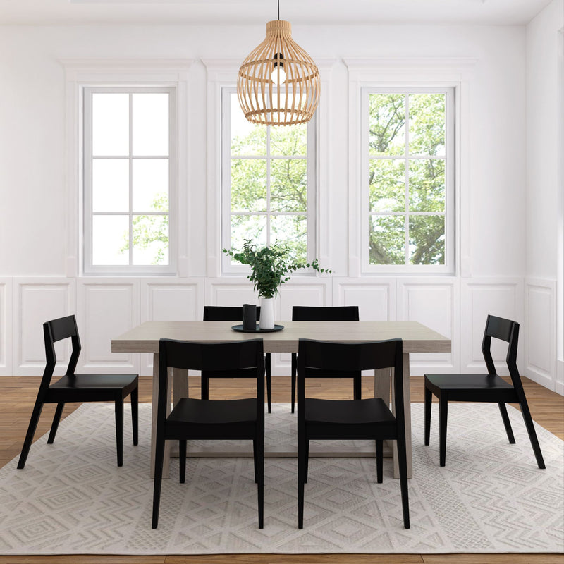 Modern dining room with black chairs, wooden table, geometric rug, and pendant light.