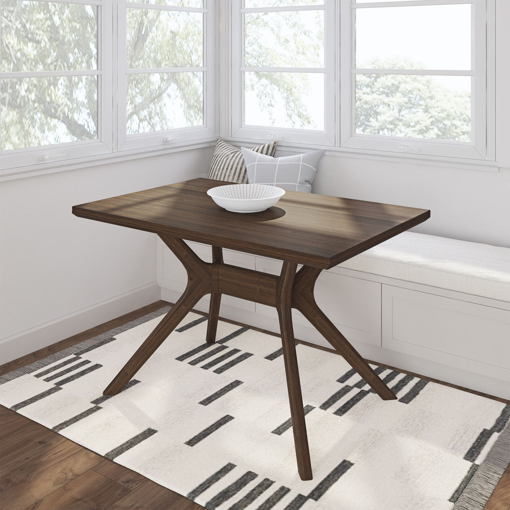 Modern wooden dining table in a sunlit corner with a stylish geometric rug and cozy seating bench.
