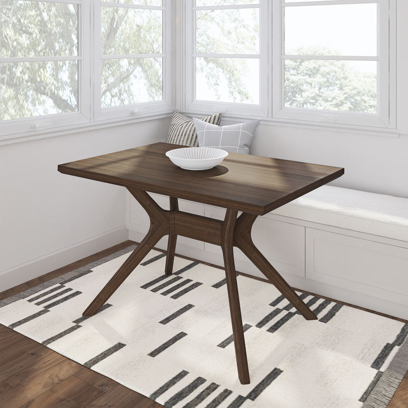 Modern wooden dining table in a sunlit corner with a stylish geometric rug and cozy seating bench.