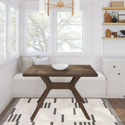 Modern dining room with wooden table, white dishware, and cozy window bench seating.