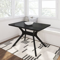 Modern black dining table with a white bowl in a bright corner nook with a minimalist design rug.