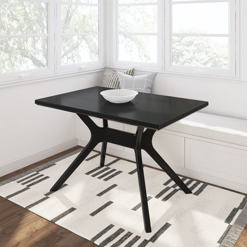 Modern black dining table with a white bowl in a bright corner nook with a minimalist design rug.
