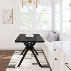 Modern black table in a well-lit dining area with windows and white cabinetry.