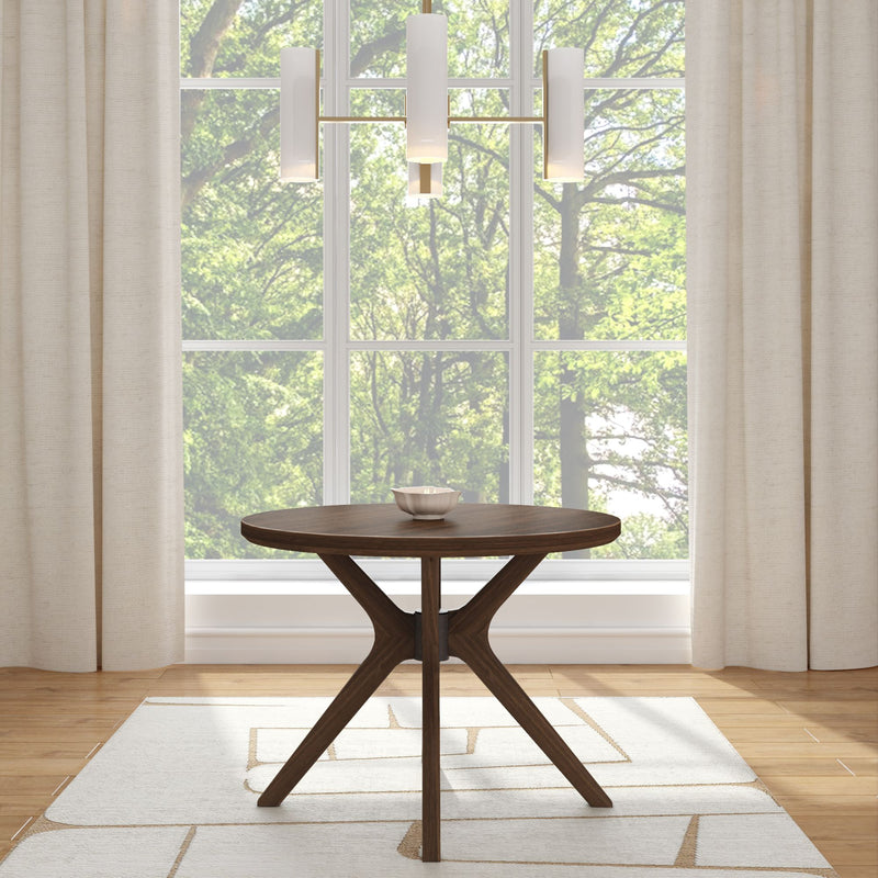 Modern round dining table with minimalist chandelier in a bright room with large windows and nature view.