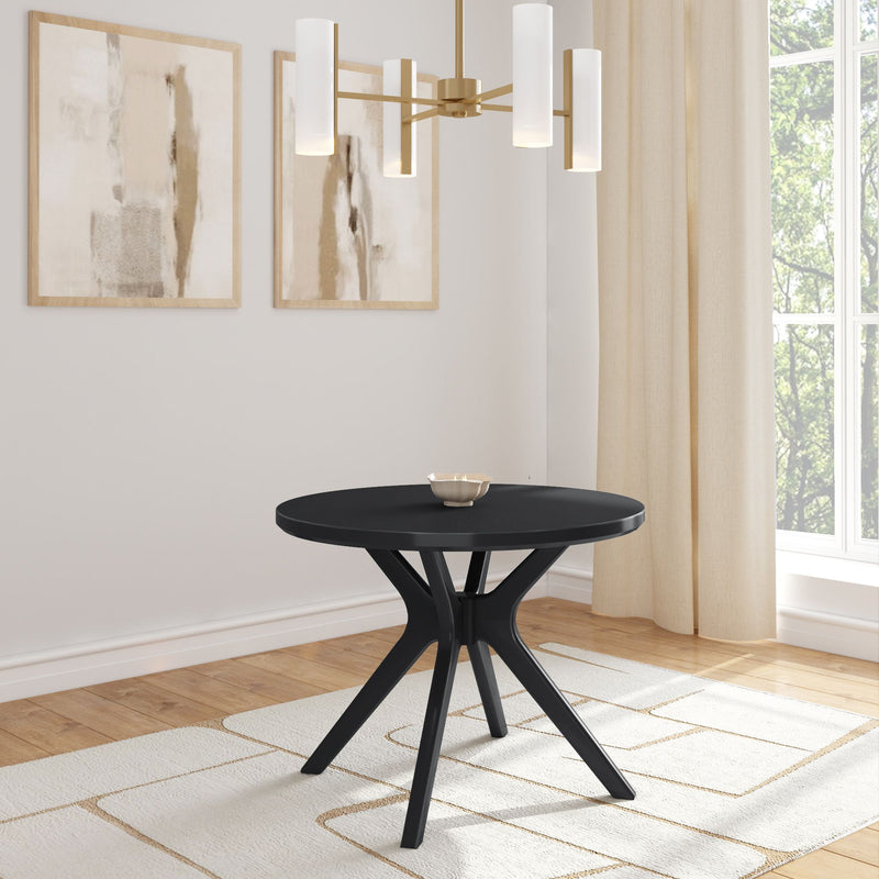 Modern round black dining table in a minimally decorated room with abstract paintings and a gold chandelier.